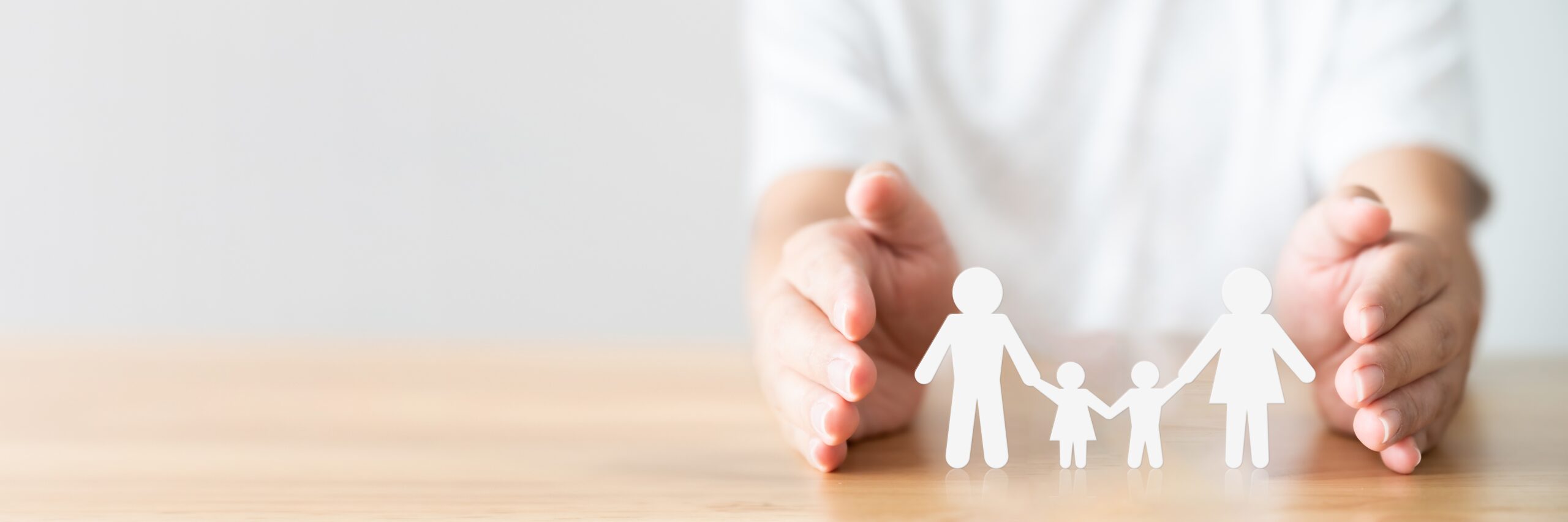 Hand,Protecting,Family,On,Wood,Table.,Healthcare,And,Life,Insurance